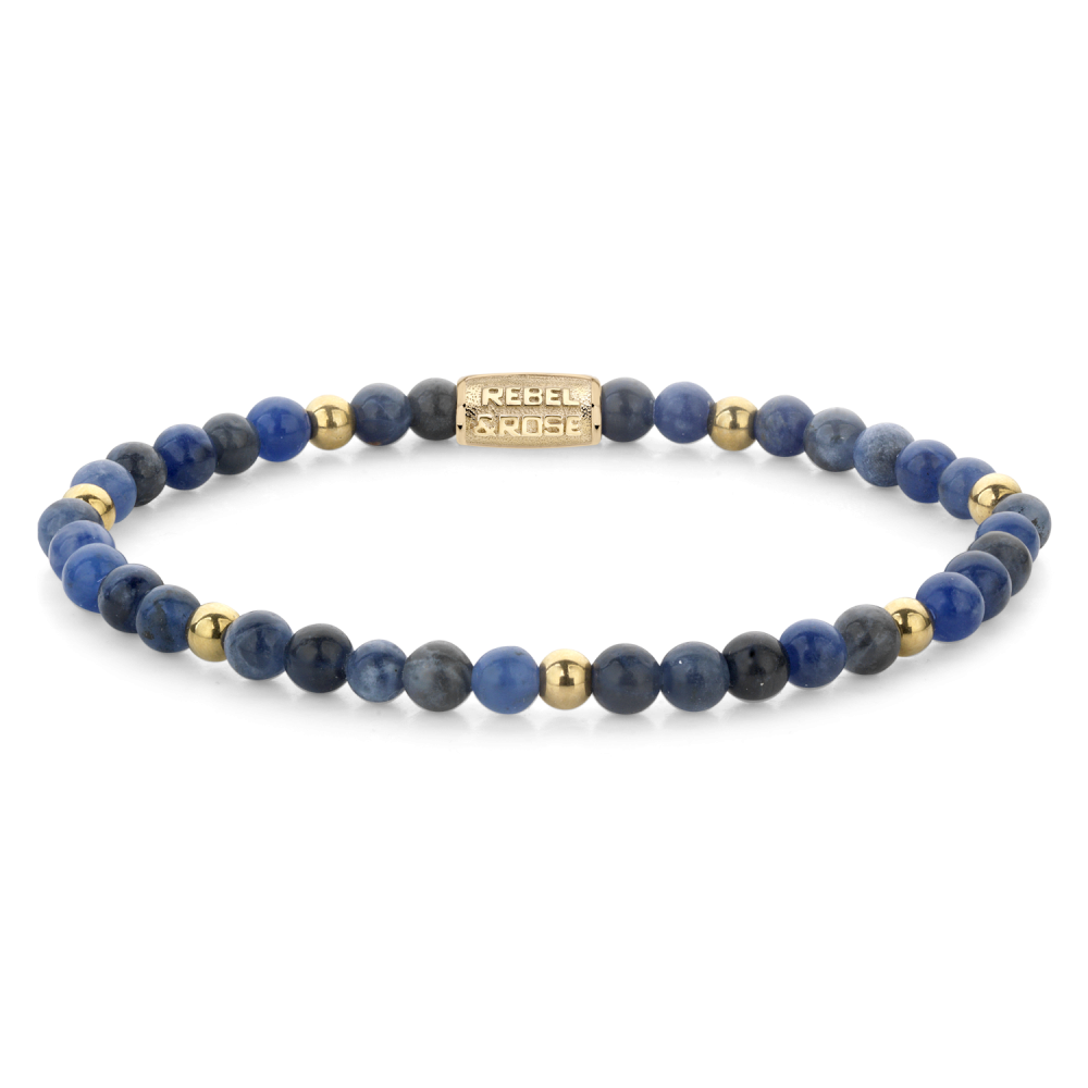 De Rebel & Rose Midnight Blue 4 mm kralenarmband voor dames heeft afwisselend sodaliet edelstenen en gouden kralen, plus een rechthoekige 18 kt geelgouden geïoniseerde bedel gegraveerd met de merknaam.