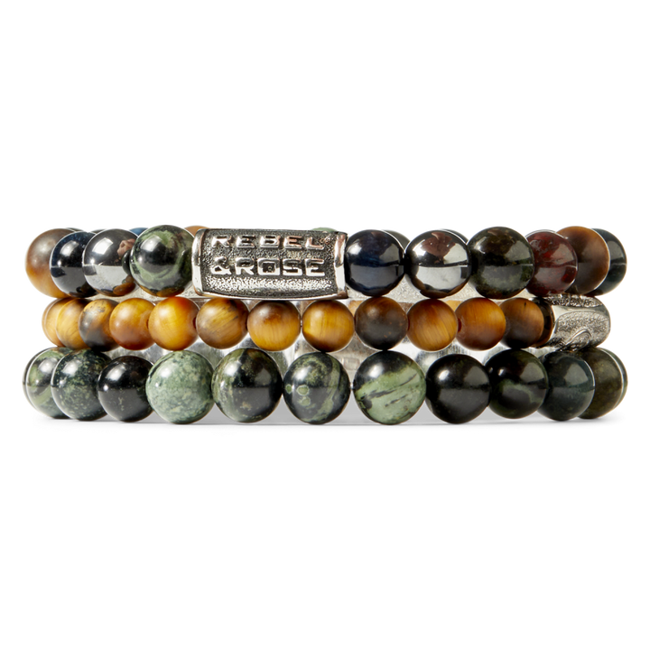 Gestapelde kralenarmbanden met gepolijste 8mm stenen in groene, bruine en zwarte tinten. De Rebel & Rose Stormy Weather Vintage herenarmband heeft een zilveren kraal met de merknaam erin gegraveerd - perfect voor een stijlvolle look.