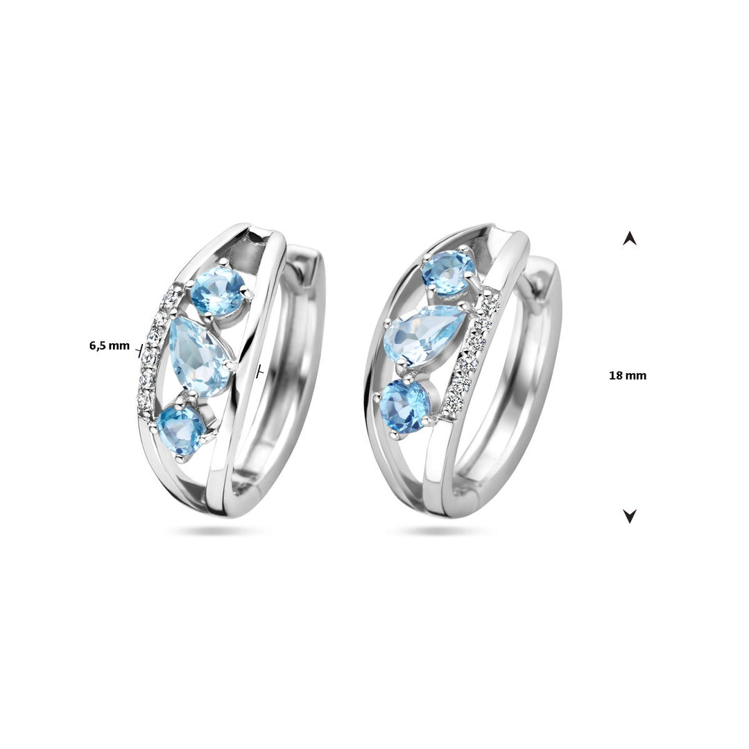 De klapoorringen topaas zilver gerhodineerd van Van der Kooij Collectie hebben drie blauwe stenen en een rij kleine heldere steentjes, zijn ca. 18 mm hoog en 6,5 mm rasideaal voor liefhebbers van dames sieraden.