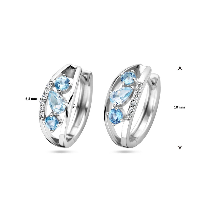 De klapoorringen topaas zilver gerhodineerd van Van der Kooij Collectie hebben drie blauwe stenen en een rij kleine heldere steentjes, zijn ca. 18 mm hoog en 6,5 mm rasideaal voor liefhebbers van dames sieraden.