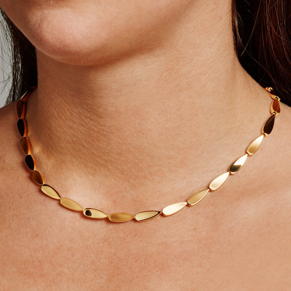 Een close-up toont een persoon die de Boccia Titanium Collier gp 08068-03 draagt, een goudkleurige ketting met ovale schakels. De ketting valt elegant om de nek, accentueert de lichte huidskleur en valt op tegen een neutrale achtergrond die de eenvoud en elegantie benadrukt.