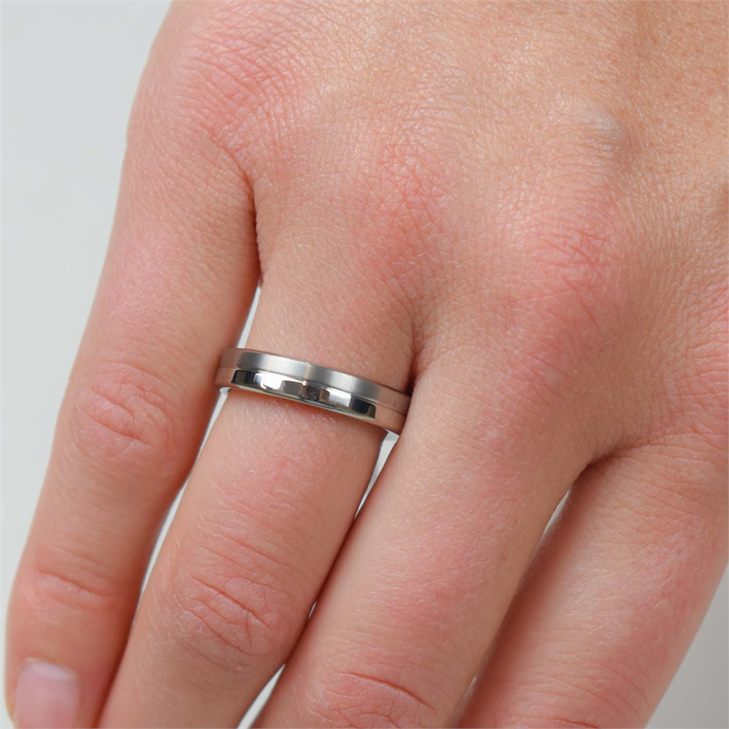 Een close-up van een hand met de elegante Boccia Titanium Ring 0129-01 om de ringvinger, waardoor de tijdloze schoonheid van de ring tegen een effen, lichte achtergrond mooi tot zijn recht komt.