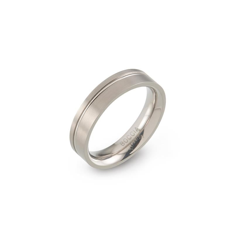 De Boccia Titanium Ring 0149-01 is een veelzijdig accessoire met een zilveren titanium buitenkant met een matte afwerking en subtiele centrale groef. Het gepolijste interieur gegraveerd met "BOCCIA" voegt elegantie toe, waardoor het perfect is voor elke collectie wanneer het in een hoek op een witte achtergrond wordt geplaatst.