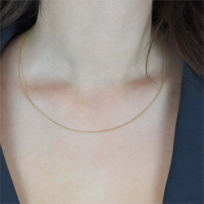 Een close-up van de nek van een vrouw die de Boccia Titanium Lengte Collier gp staal 0802-02 van Boccia draagt, waarbij een deel van haar donkere haar zichtbaar is en ze een donker topje draagt.