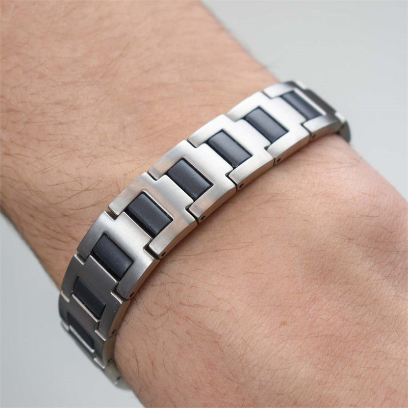 Een close-up van een pols met de Boccia Titanium Armband rubber 0334-01, met dikke zilveren schakels en zwarte rubberen accenten van Boccia, tegen een effen, lichte achtergrond.