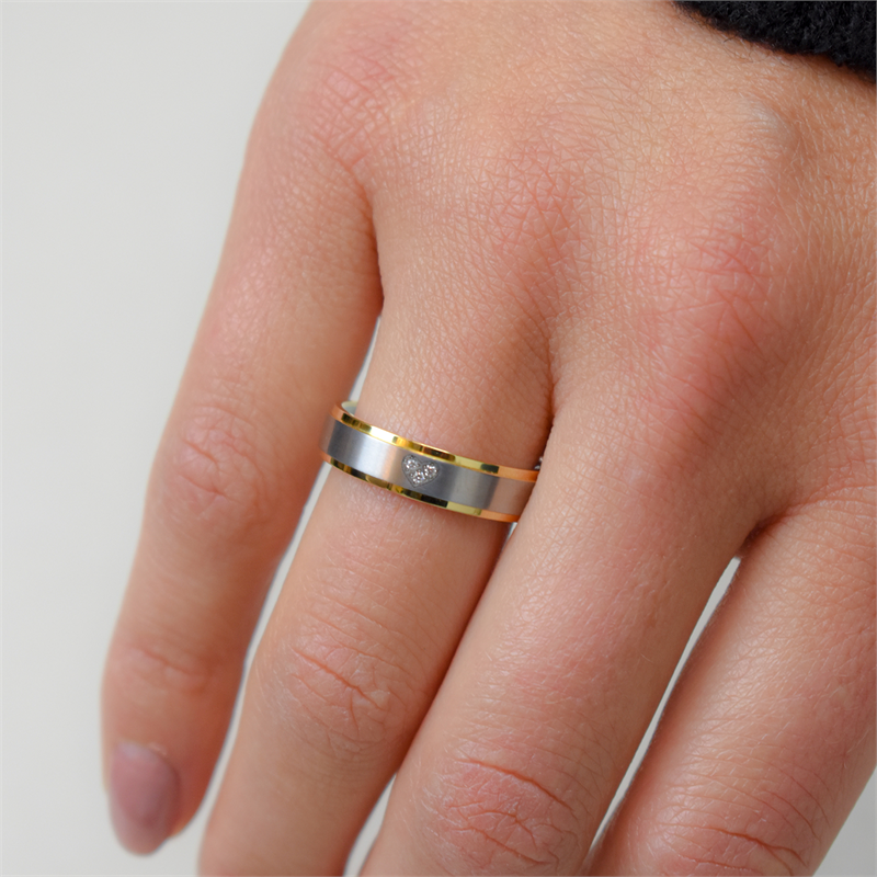 Een close-up van een hand die de Boccia Titanium Ring Bicolor dia 3/0.015 (0134-06) van Boccia draagt, met zilver en goud titanium met een centrale diamant. De nagels van de draagster zijn kort en natuurlijk, tegen een effen lichte achtergrond.