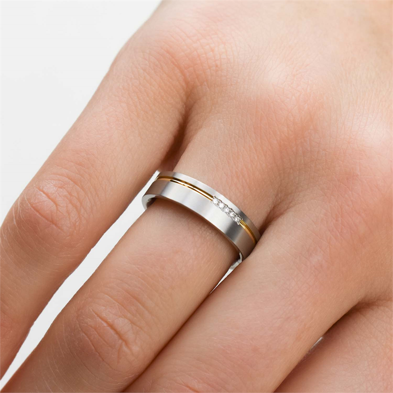Een close-up van een hand met de Boccia Titanium Ring Bicolor dia 5/0.025 - 0149-04, met een dunne gouden streep en kleine diamanten op de ringvinger.