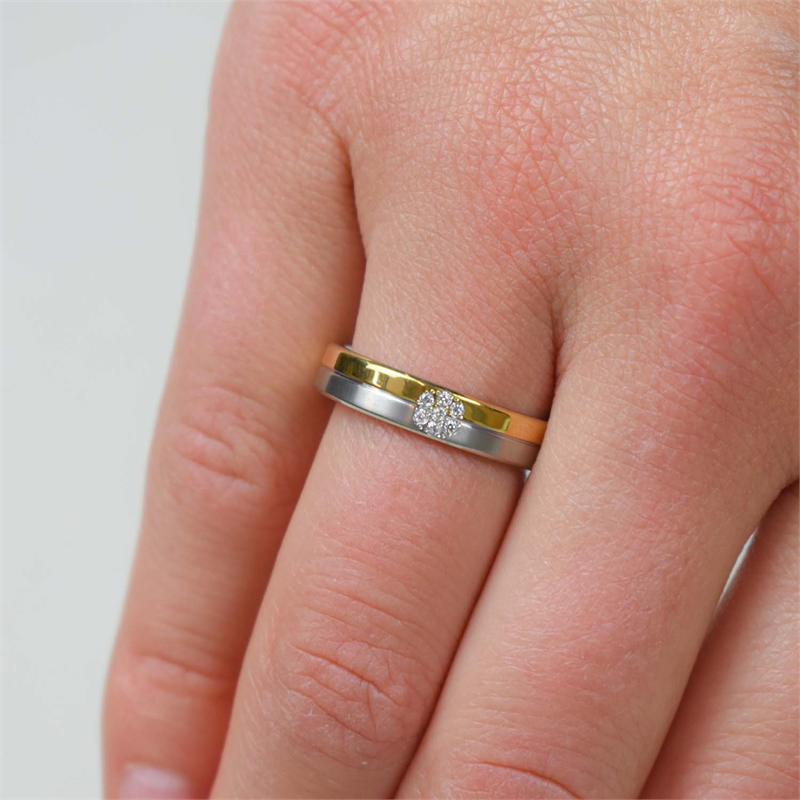 Een close-up van een hand die de Boccia Titanium Ring Bicolor dia 7/0.035 - 0129-06 draagt, een elegante gouden en zilveren ring van Boccia met een centraal cluster fonkelende diamanten, glanzend tegen een lichte achtergrond.