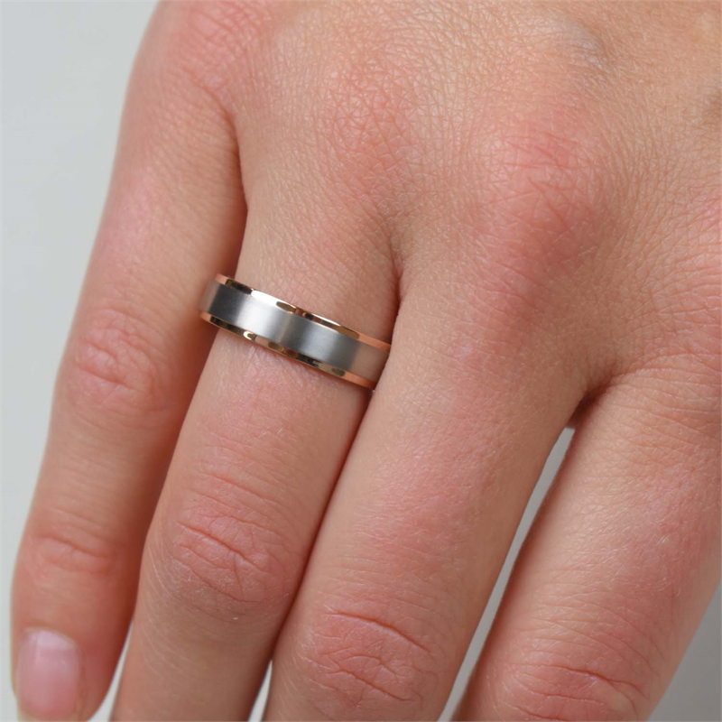 Een close-up van een hand met de Boccia Titanium Ring Bicolor rgp 0134-03 van Boccia aan de ringvinger tegen een lichte achtergrond.