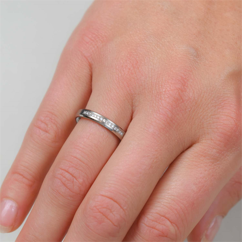 Een close-up van een hand die de Boccia Titanium Ring dia 15/0.075 - 0120-04 van Boccia draagt, met kleine ingebedde steentjes op de ringvinger tegen een effen achtergrond.