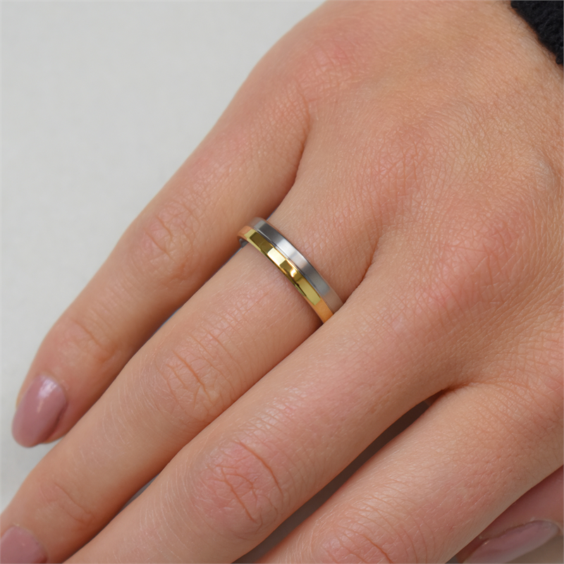 Een close-up van een hand met lichtroze nagels met de Boccia Titanium Ring Bicolor 0129-02, verkrijgbaar in zowel goud- als zilvertinten. Deze elegante Boccia-ring is perfect voor liefhebbers van stijlvolle sieraden en valt mooi op tegen een lichte achtergrond.