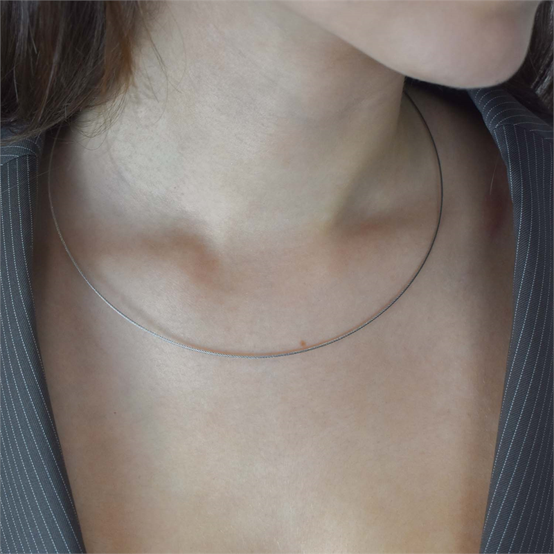 Een persoon draagt een Boccia Titanium Lengte Collier staal 0802-01 met een bajonetsluiting, die zijn blanke huid accentueert tegen een open-hals pinstripe kledingstuk. De focus ligt op de nek en het sleutelbeengebied.