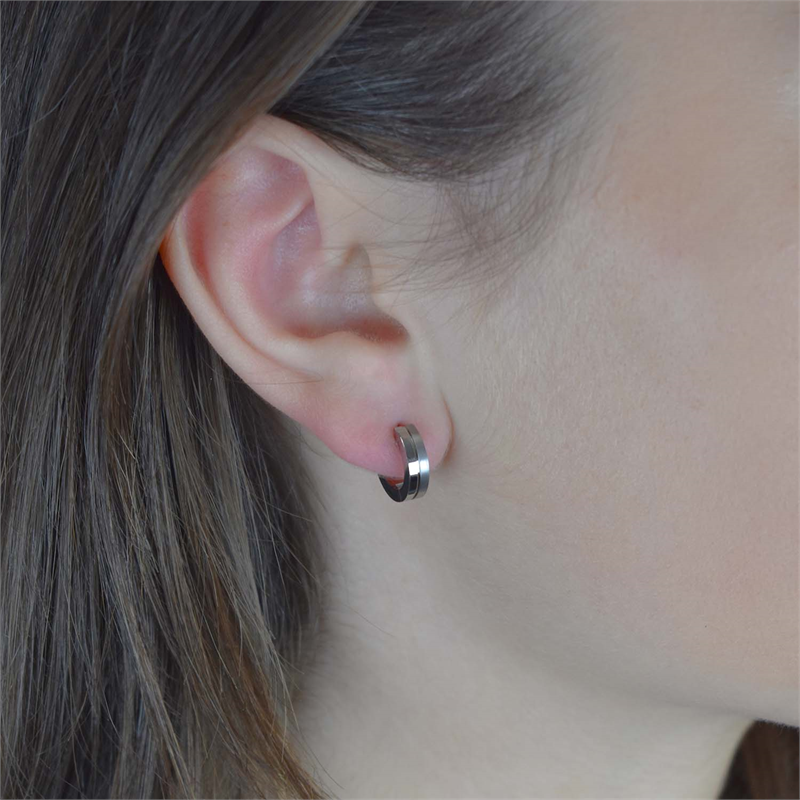Close-up van het oor van een lichtgekleurd persoon met een Boccia Titanium Oorring 0510-01 van Boccia. De kleine, zilverkleurige oorring is scherp in beeld, met een deel van de wang en bruin haar zichtbaar op de achtergrond.