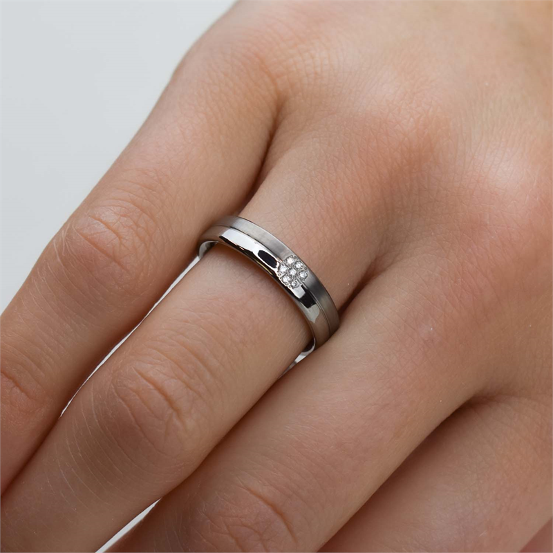 Een close-up van een hand die de Boccia Titanium Ring dia 7/0.035 - 0129-05 van Boccia draagt, een zilverkleurige band met een klein diamanten cluster, getoond op de ringvinger tegen een neutrale achtergrond.