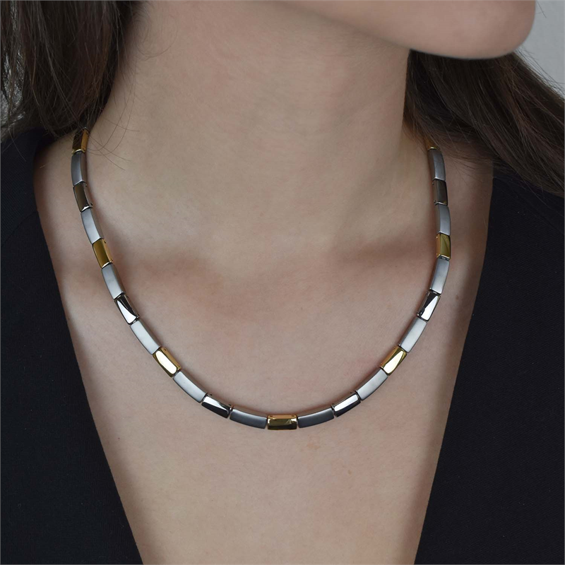 Een close-up van de Boccia Titanium Collier bicolor 08043-02 van Boccia, een tweekleurige schakelketting met afwisselend zilveren en gouden rechthoekige schakels, gecombineerd met een zwarte top.