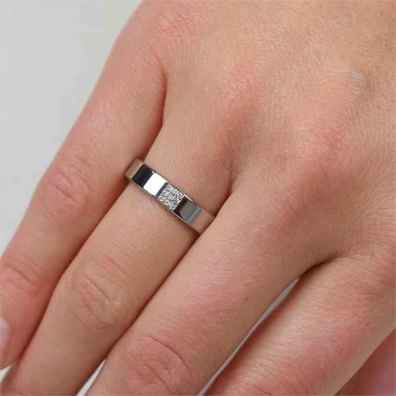 Een close-up van een hand die de Boccia Titanium Ring dia 9/0.045 - 0121-02 draagt, met een rechthoekig cluster van heldere stenen op de ringvinger tegen een lichte achtergrond-een modern Boccia sieraad voor liefhebbers van diamanten.