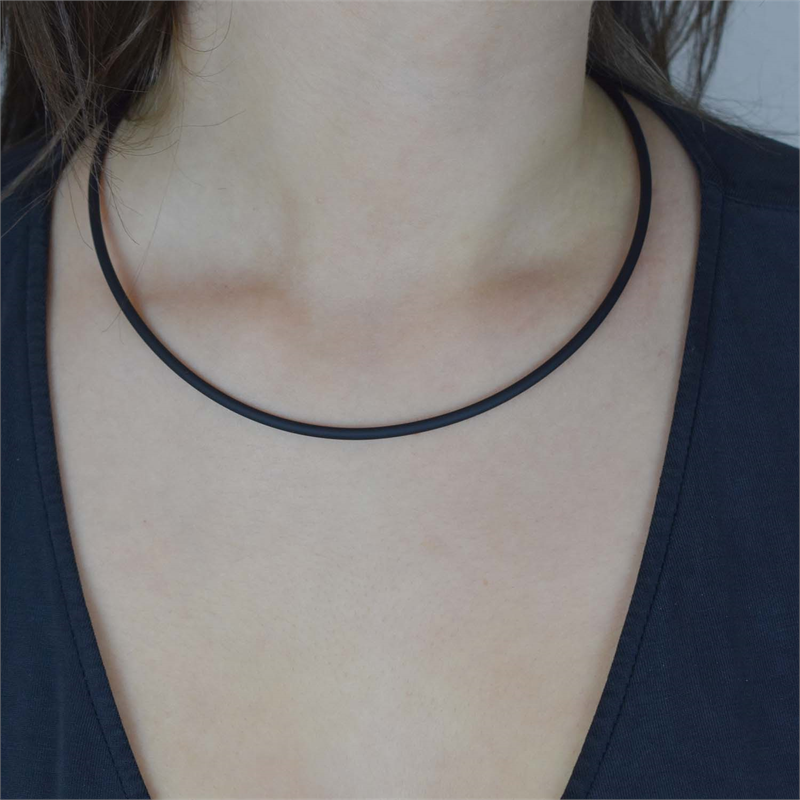 Een persoon draagt de Boccia Titanium Lengte Collier rubber 0827-01 choker van Boccia met een donker shirt met V-hals, afgebeeld vanaf de schouders tegen een neutrale achtergrond.