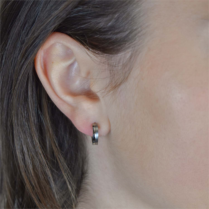 Close-up van het oor van een persoon die Boccia Titanium Oorringen 0563-01 draagt. De achtergrond is wazig en het haar is achter het oor gestopt om de elegante Boccia-sieraden te benadrukken.