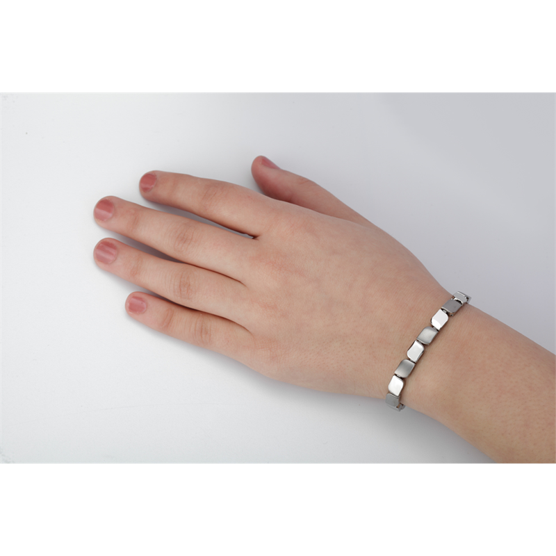 Een linkerhand met korte nagels draagt een eenvoudige Boccia Titanium Armband 03007-01, met zilveren vierkante schakels op een witte achtergrond.