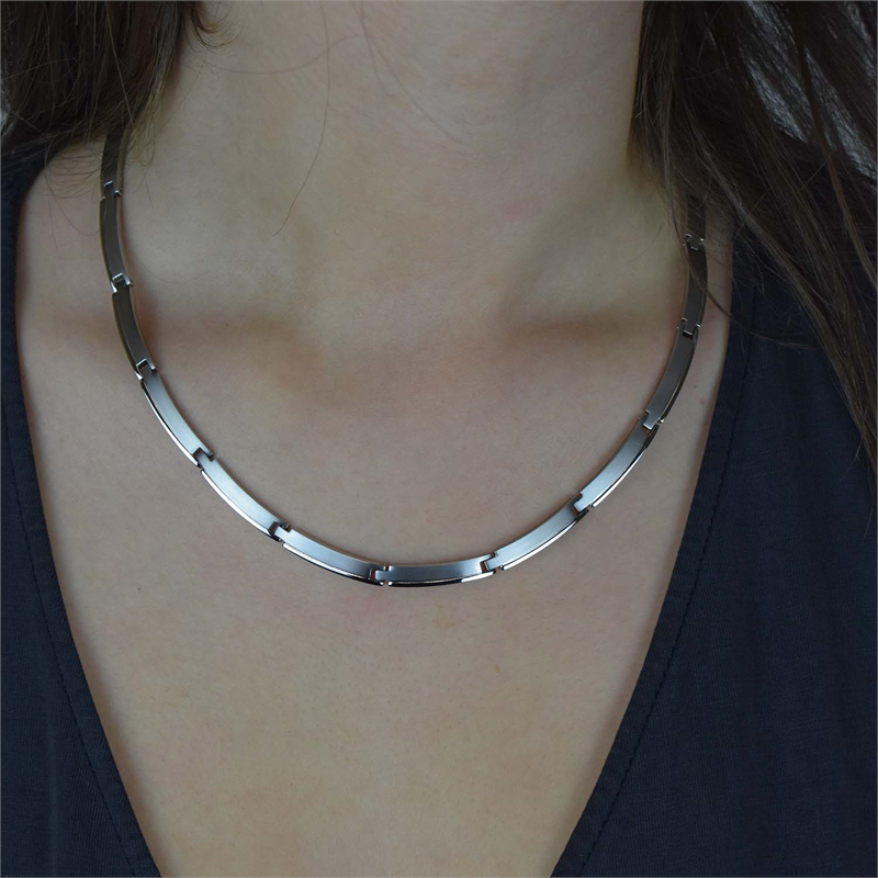 Een close-up van een persoon die de Boccia Titanium Collier NL 08028-01 draagt – minimalistische rechthoekige zilveren schakels van Boccia – gestyled met een donker topje met V-hals, waarbij de ketting elegant op het sleutelbeen rust.