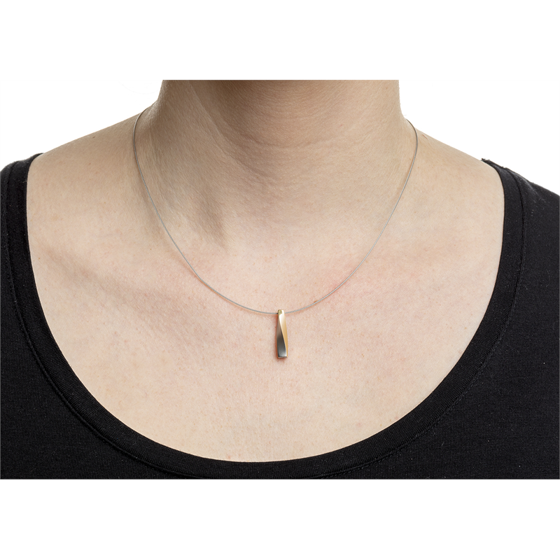 Een persoon in een zwart topje draagt een Boccia Titanium Hanger Bicolor 07018-02 ketting met een strakke, langwerpige hanger die een minimalistisch design laat zien. De achtergrond is effen wit.
