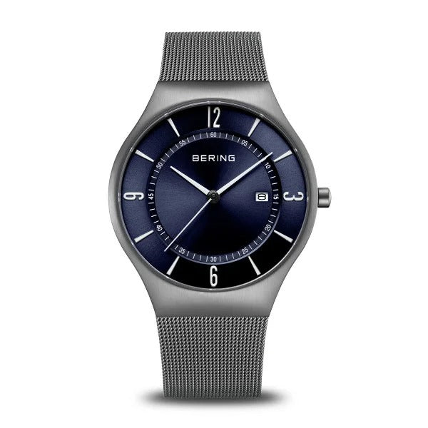 De Bering 15940-378 is een stijlvol herenhorloge met een metalen mesh band, ronde blauwe wijzerplaat, saffierglas, witte uurmarkeringen en een datumvenster bij 3 uur.