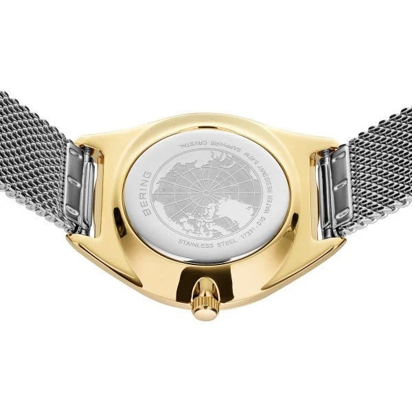 De achterkant van de Bering 17331-010 dameshorloge toont een gouden kast met een zilverkleurige mesh band, met een gegraveerd kaartontwerp en tekst die het merk Bering, materiaaldetails en de solar horloge functionaliteit benadrukt.
