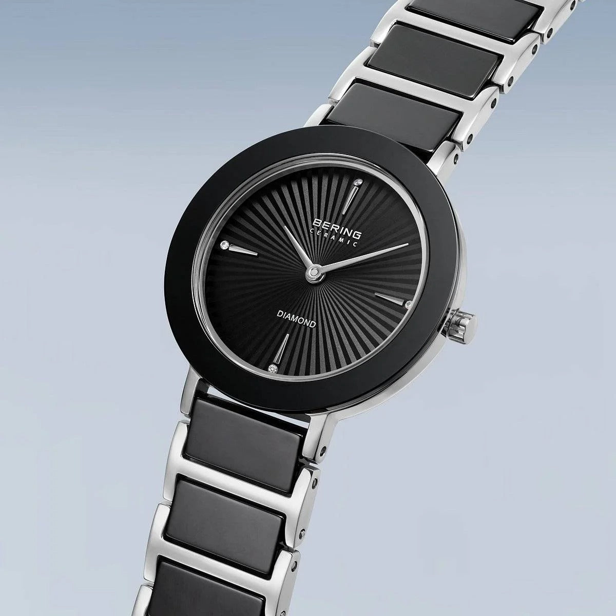 Het Bering dames horloge 11429-702 heeft een zwarte en zilveren keramische/roestvrijstalen band, ronde zwarte wijzerplaat, minimalistische wijzers, slanke wijzers en duurzaam saffierglas - een elegante keuze van Bering.