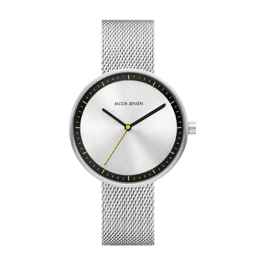 Zilveren horloge met mesh-band, witte wijzerplaat en gele accenten op de wijzers.