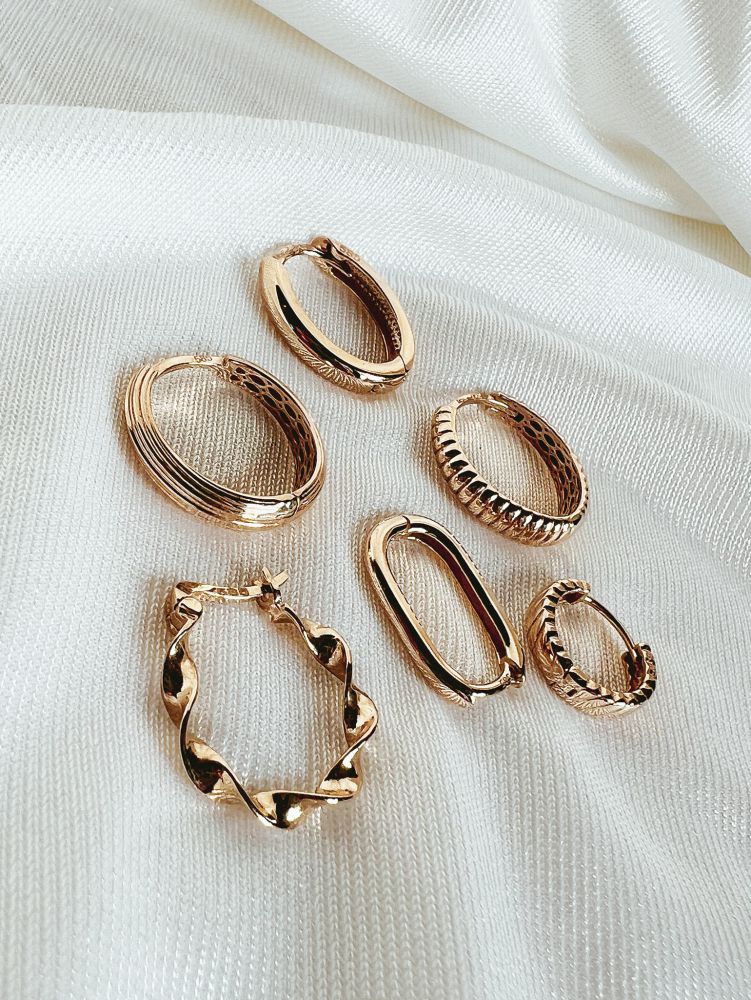 Zes paar Geelgouden Oorringen met Geribbeld Design - Van der Kooij Tijdloos Sieraad van Excellent Jewelry, gemaakt van 14 karaat goud met unieke texturen en vormen, staan op een witte stoffen achtergrond.