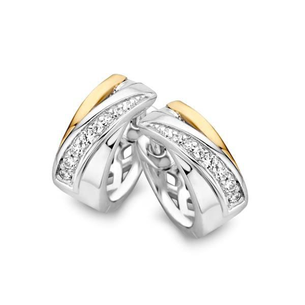 Zilver-gouden oorringen met een golvende vorm en zirkonia's in een rij aan de voorkant.