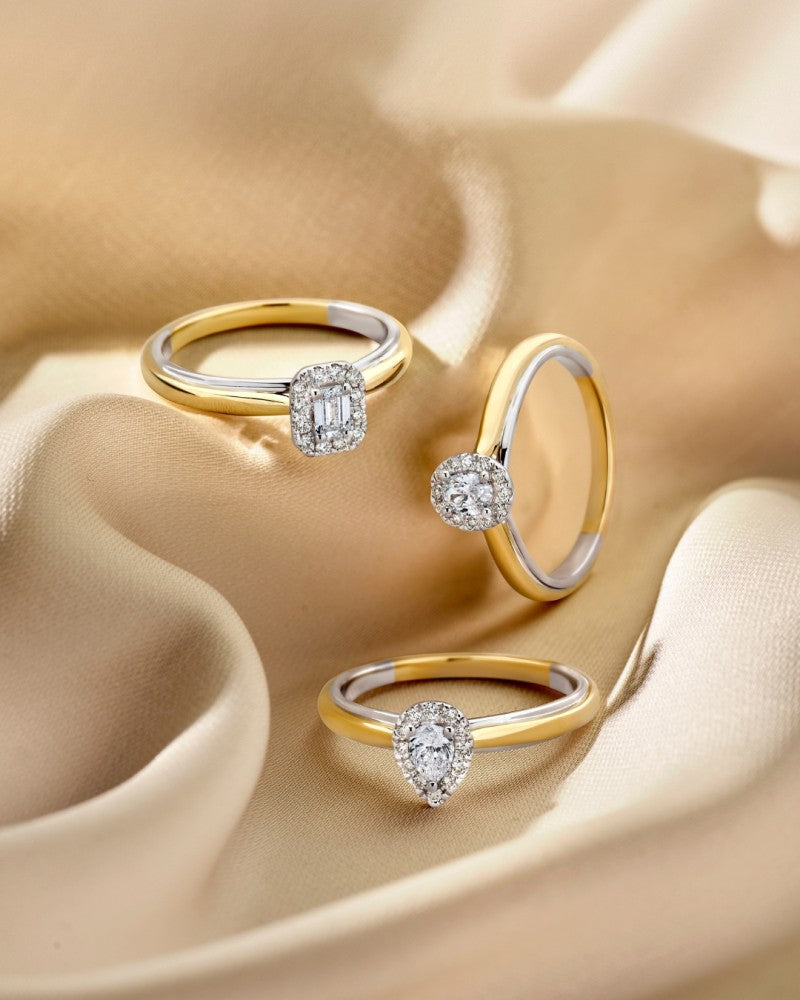 Drie gouden en zilveren ringen met diamanten - waaronder een smaragdgeslepen diamanten 14k bicolor gouden ring van Excellent Jewelry - worden getoond op zacht gedrapeerd beige satijn.