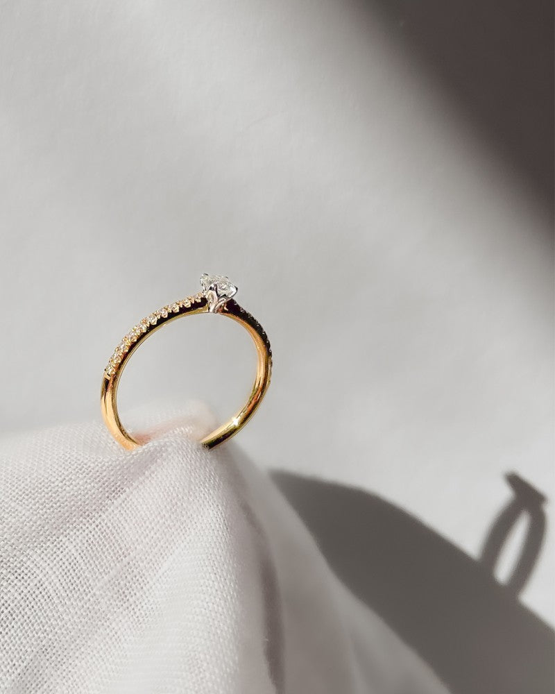 De Elegante bicolor solitair ring met briljant geslepen diamant 0.35 crt. van Excellent Jewelry schittert op zachte witte stof, waarbij licht en schaduw zorgen voor een minimalistische en elegante uitstraling.
