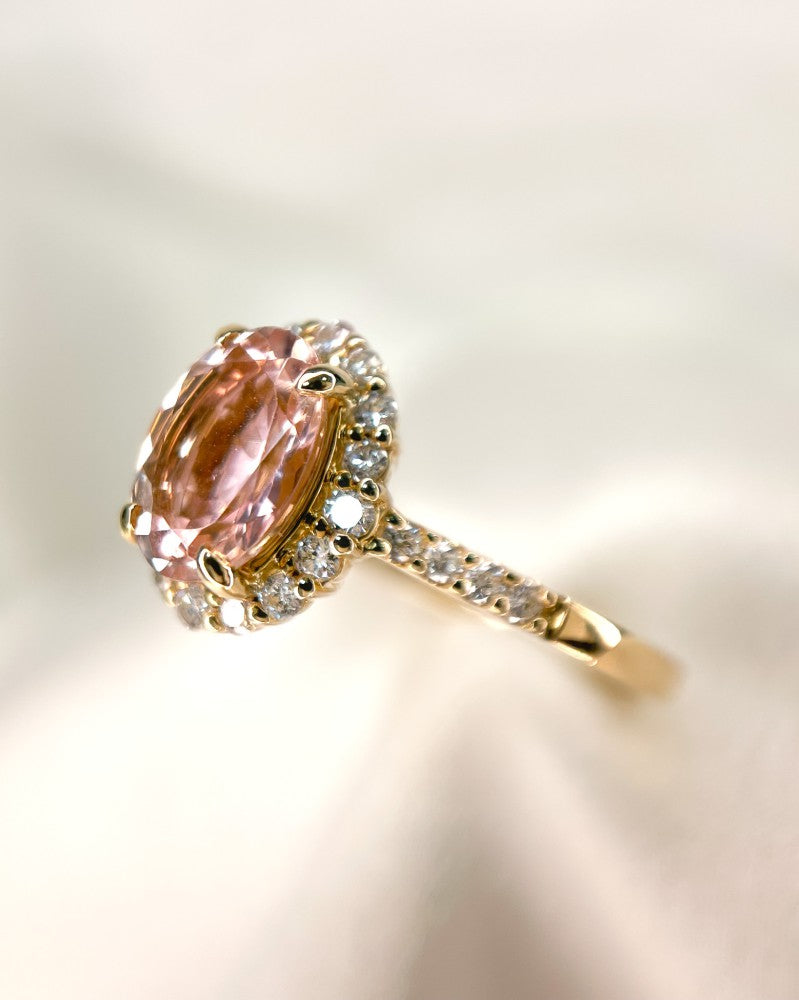 De Elegante Geelgouden Ring met Roze Morganiet en Briljante Diamanten van Excellent Jewelry toont een ovale roze morganiet omringd door schitterende diamanten, met extra diamanten op de band, tegen een zachte, lichte achtergrond.