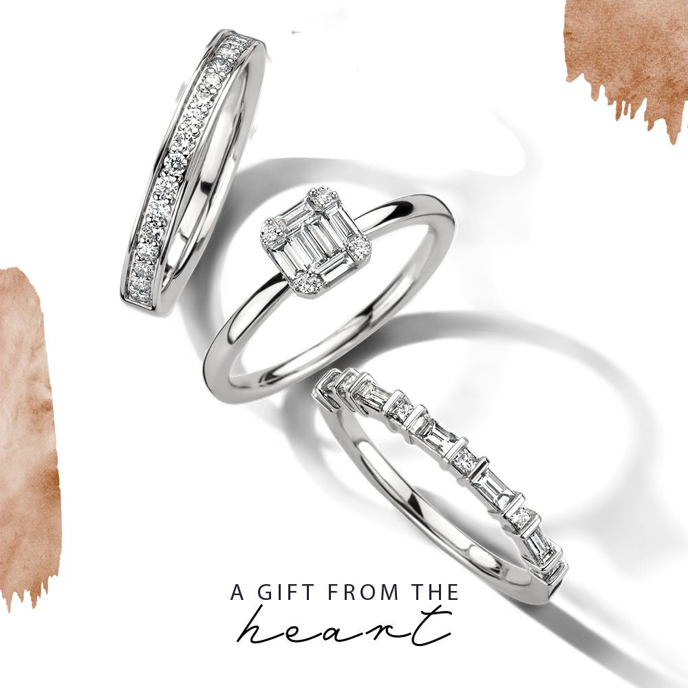 Een elegante witgouden diamanten ring met princessen- en baguetteslijpsel (0,36 crt) van Excellent Jewelry schittert op een witte achtergrond met daaronder "A GIFT FROM THE heart" en bruine aquarelaccenten die het tafereel omlijsten.
