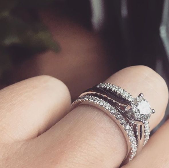 Een close-up van een hand die twee gestapelde ringen draagt: de Elegant White Gold Solitaire Ring met een briljant van 0,74 karaat diamant van Excellent Jewelry, gecombineerd met een bijpassende trouwring met diamant.