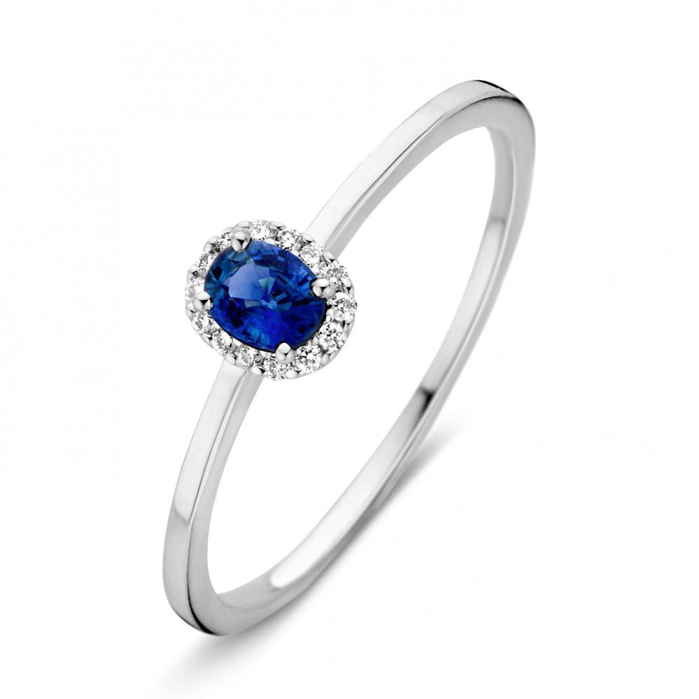 Witgouden damesring met een ovale blauwe saffier omringd door een cirkel van kleine diamanten.