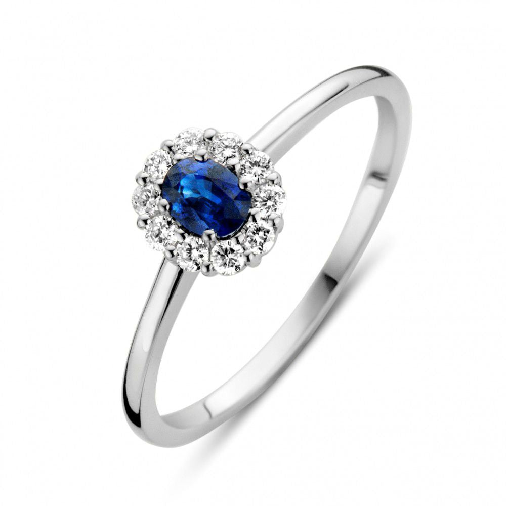 Witgouden ring met ovale blauwe saffier omringd door een cirkel van kleine diamanten.