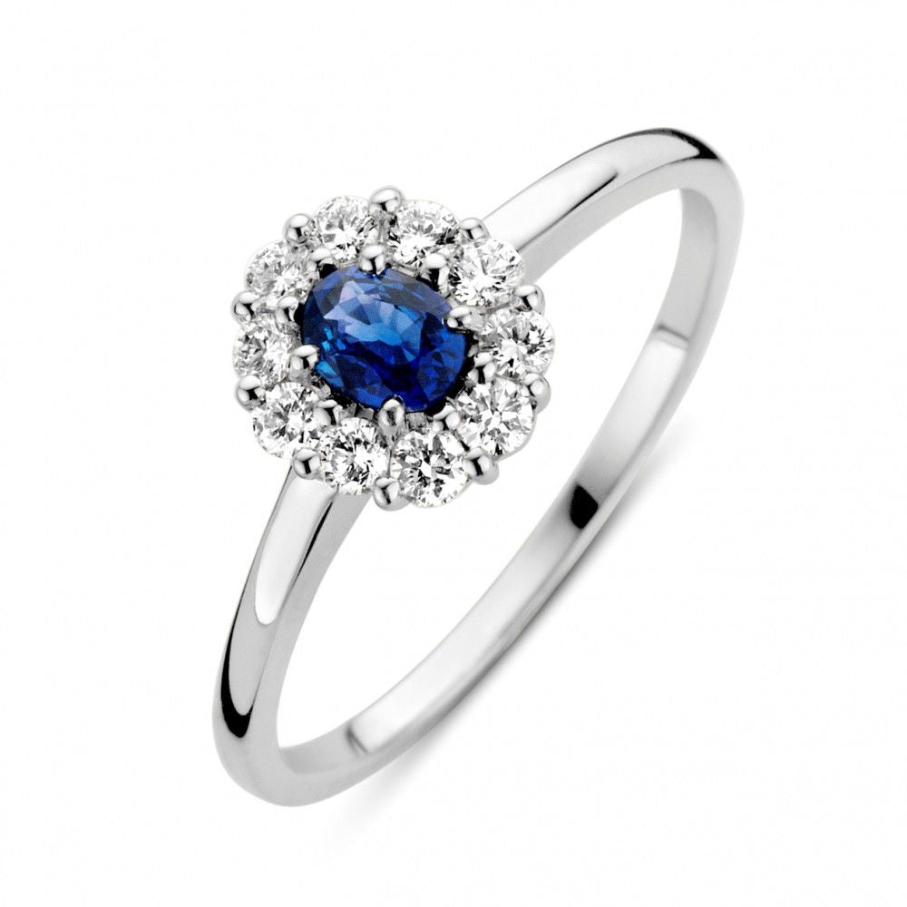 Witgouden ring met een ovale blauwe saffier omringd door een cirkel van diamanten.