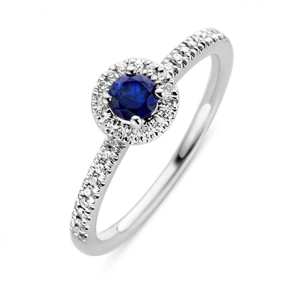 Witgouden ring met een ronde blauwe saffier omringd door een cirkel van kleine diamanten.