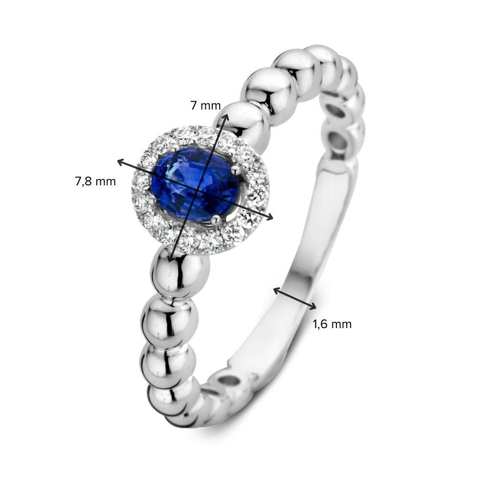 De 14 karaat witgouden rijring met blauwe saffier en 0,14 ct diamanten van Excellent Jewelry heeft een ovaal middensteen (7 mm), een zetting van 7,8 mm breed en een bandbreedte van 1,6 mm.
