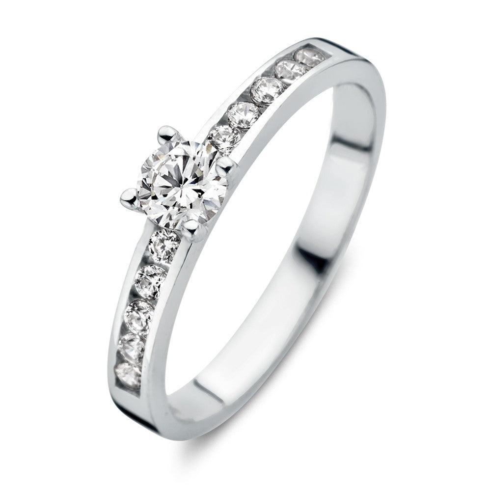 De Excellent Jewelry Witgouden Damesring met Zirkonia's - Subtiele Elegantie is een 14 karaat witgouden damesring met een centrale ronde zirkonia en kleinere zirkonia's langs de band, getoond op een witte achtergrond.