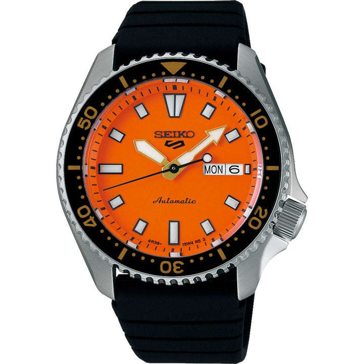 De Seiko 5 Sports heren horloge SRPL89K1 van Seiko heeft een fel oranje wijzerplaat, zwarte lunette, zwarte siliconen band, lichtgevende markers, dag-datum weergave, witte wijzers en een zilverkleurige roestvrijstalen kast geïnspireerd op de SKX399.