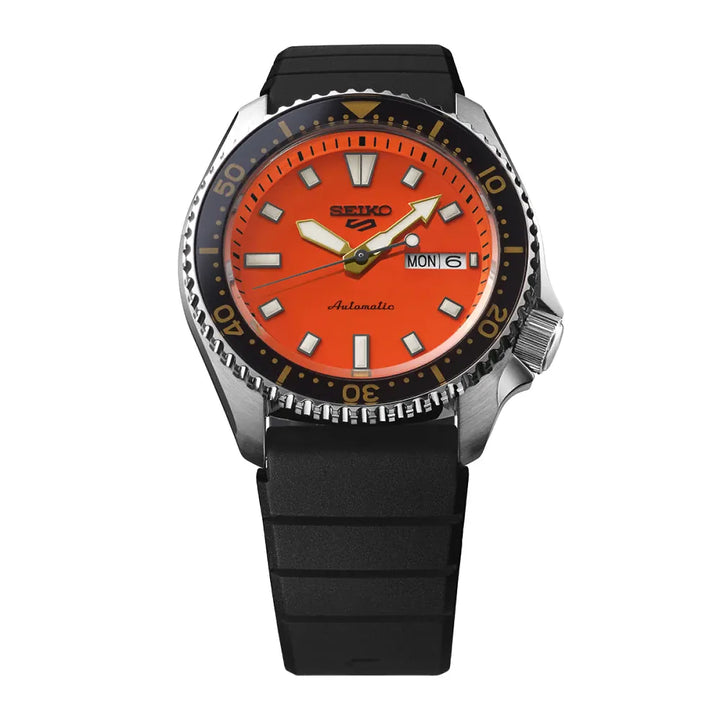 De Seiko 5 Sports heren horloge SRPL89K1 van Seiko heeft een fel oranje wijzerplaat, zilverkleurige en gele wijzers, opvallende witte uurmarkeringen, een zwarte draaibare lunette met gouden accenten en een zwarte rubberen band. Datum en dag staan op 3 uur. Geïnspireerd op de SKX399.