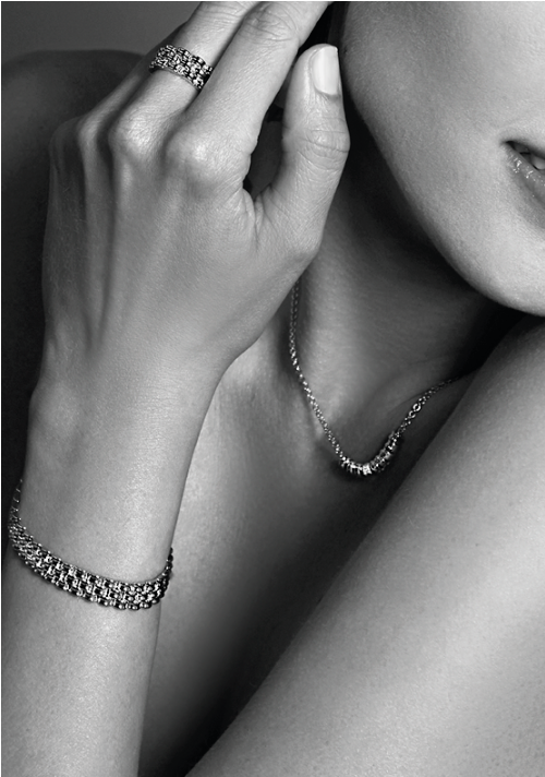 Een zwart-witfoto legt een persoon vast met zijn kin aangeraakt, met de Zinzi Ketting Zilver Mvc22 versierd met witte zirkonia. De elegante ketting, bijpassende armband en ring stralen verfijning uit.
