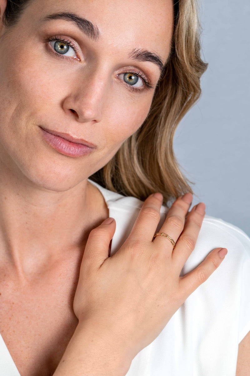 Gouden ring met een verfijnde afwerking, gedragen op de ringvinger van een model.